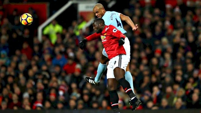 Romelu Lukaku battling for the ball in the air with Vincent Kompany